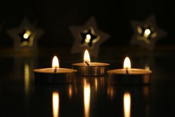 three candles are burning on a dark background. High quality photo