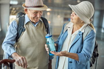 Obraz na płótnie Canvas Elderly lady with a bottle talking to her husband