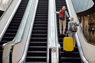 Two senior tourists using the moving staircase