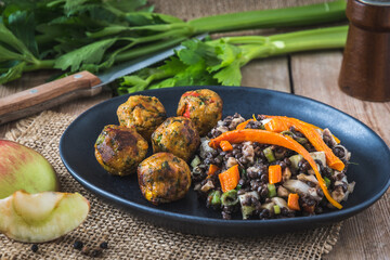 Roasted vegetable balls with lentil salad on black plate on wooden table, vegan food concept