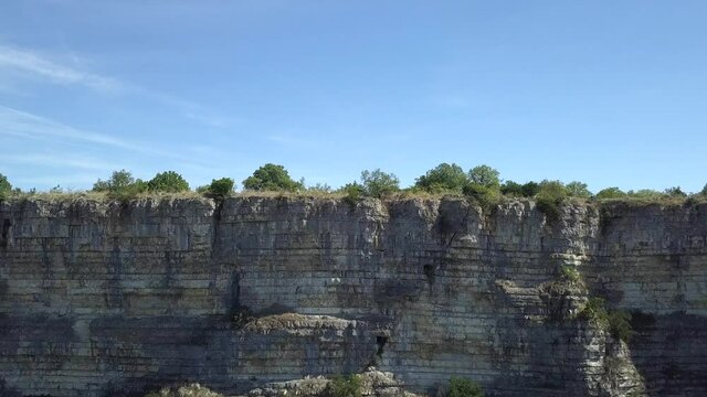 Aerial: Dramatic striated limestone cliff to Oppidum de Jastres on top