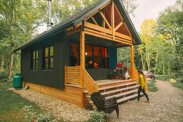 Foto op Plexiglas Vacation rental forest lodge countryside cabin by the lake for holidays in the wilderness. Woman entering her house home away from home. © Maridav
