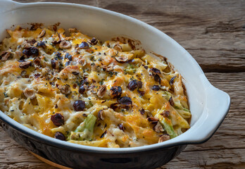 Casserole with  pasta, couliflower, brocoli and  cheddar cheese on wood deck.  Selective  focus.