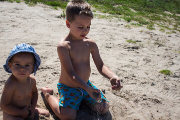 a boy and girl play with sand on the river bank
