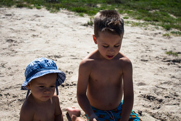 a brother plays with younger sister play in the sand