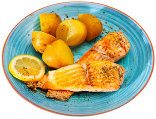 Appetizing fried salmon fillet served with boiled potatoes in their skins and lemon slice on blue plate. Isolated over white background