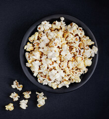 Scattered salted popcorn in a bowl  on black background with copy space. Homemade Popcorn  Top view. .