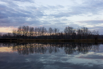 View of the lake at sunset. The clouds are reflected in the water.