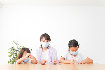 マスクを付けて勉強をする子供と塾講師