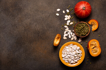 small orange pumpkins and pumpkin seeds on a dark table