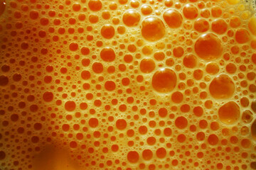 Bright yellow foam from a beaten egg. Egg in a glass bowl.