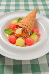 Refreshing melon ice cream with a cone in a white plate. Delicious summer dessert. Cold ice cream fruit sorbet.