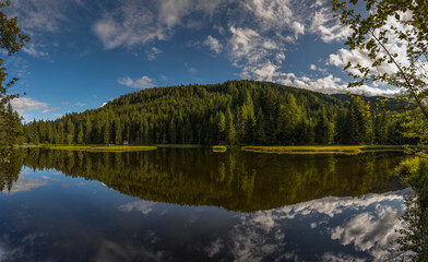 clear mountain lake with reflection from the forest with clouds panorama