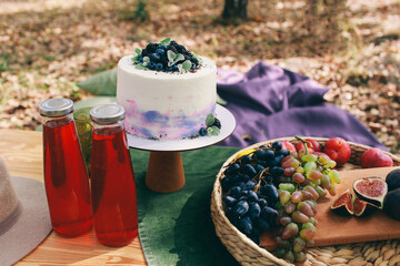 Outdoor Gender Reveal Party Decorations. girl or boy. beautiful photo zone with cake and fruits.
autumn decor with purple and green color. Two glasses of the red wine and tasty food and accessories 