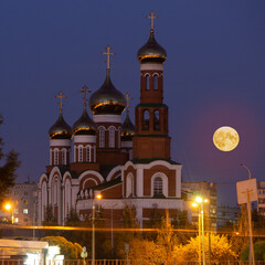 Obraz premium Nativity of Christ Cathedral at Stepants 5 in Omsk and the rising full moon next to the church. Full moon over the temple.
