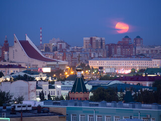 Full pink moon rising over the musical theater. Omsk city center, Lenin square.