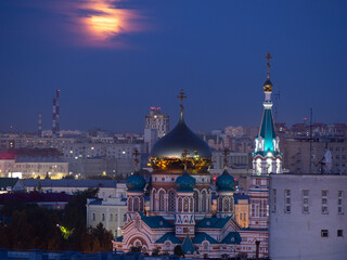 Obraz premium The rising full pink moon over the Assumption Cathedral in Omsk.