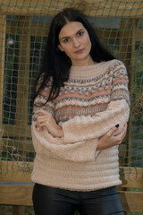 Black-haired woman posing in autumn park in knitted sweater
