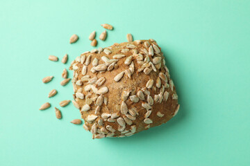 Bun with sunflower seeds on mint background