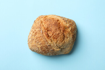 Fresh baked bun on blue background, close up