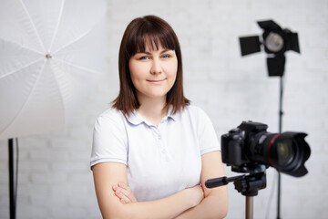 portrait of female photographer posing with camera and flashlights in studio