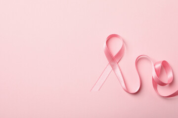 Pink awareness ribbon on pink background, space for text