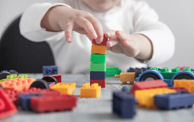 Fototapeta premium Little girl playing with colorful construction plastic cubes.