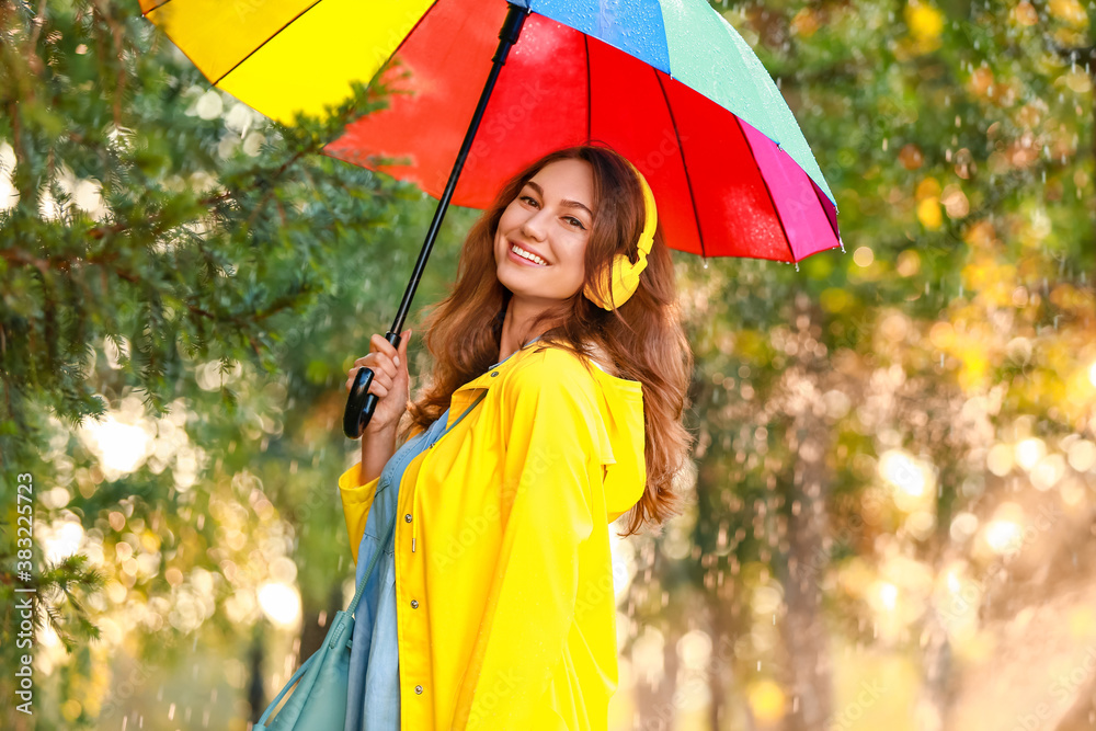 Wall mural beautiful young woman with umbrella wearing raincoat in park