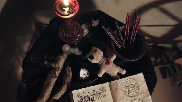 Items for magic ceremonies and rituals. Voodoo doll, candle, pentagram book in the dark. Amulets for witchcraft