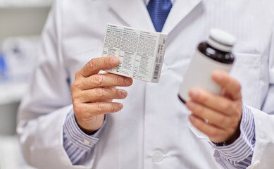 medicine, pharmaceutics, healthcare and people concept - close up of senior male pharmacist with drugs at pharmacy