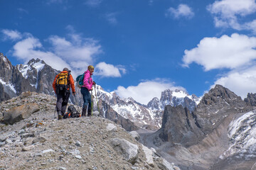 Fototapeta premium Not young spouses and their dog climbed to a height of 3300 meters above sea level. They are very happy that they were able to go so far. They jump, laugh against the background of snowy mountains.