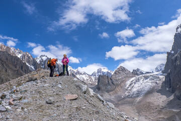 Not young spouses and their dog climbed to a height of 3300 meters above sea level. They are very happy that they were able to go so far. They jump, laugh against the background of snowy mountains.