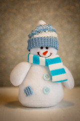 Smiling snowman toy dressed in scarf and cap.