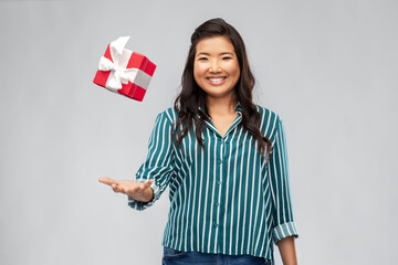 birthday present and surprise concept - happy asian young woman with gift box hanging in air over grey background