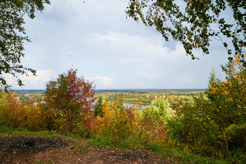 Autumn landscape with top view on the river through branches of trees with yellow leaves in autumn day