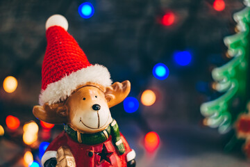 deer dressed as santa claus on the background of a dark wall with a christmas garland