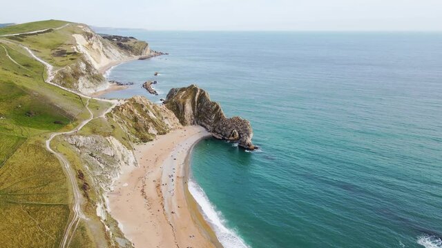Aerial drone shot tracking around to reveal the famous Durdle Door rock formation on the jurassic coast in Dorset.