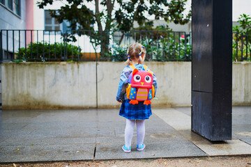 Adorable toddler girl with funny backpack ready to go to daycare, kindergarten or school