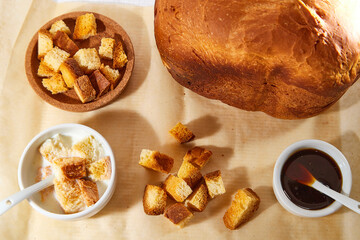 Square toasted pieces of homemade delicious rusk, hardtack, Dryasdust, zwieback, bread, Liquid honey and plate with milk in a white plate on a white tablecloth.