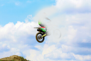Photo action shot of Motocross racing sports in cloud with blue sky.