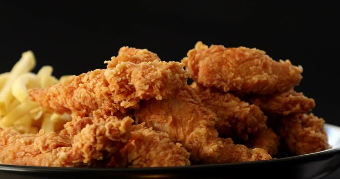 Macro view of Tasty french fries and crispy chicken nuggets with mustard and ketchup at black background