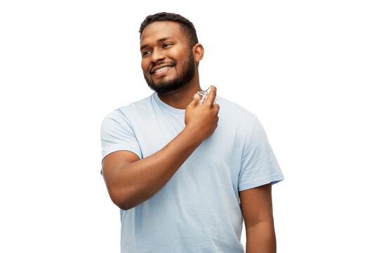 male perfumery, grooming and people concept - happy smiling young african american man with perfume over white background