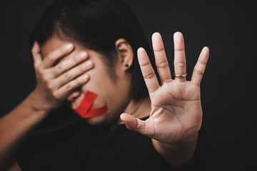 Woman blindfold wrapping mouth with red adhesive tape and show hand sign stop abusing violence and...