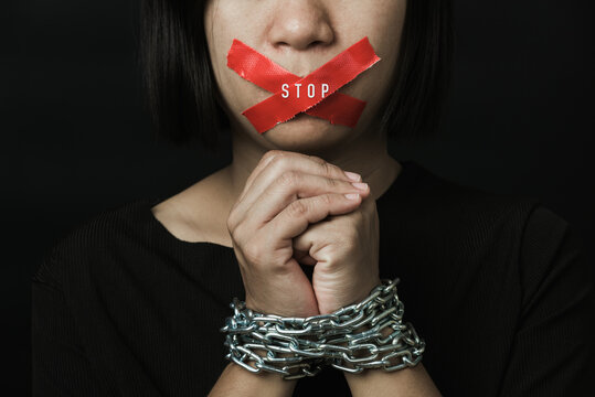 Asian woman blindfold wrapping mouth with red adhesive tape and she was hand tethered on black background. Freedom speech censorship and stop talk, International Human Right day