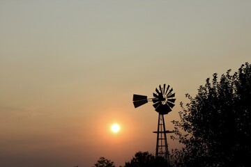 windmill at sunset with a smokey sky from the Forrest fires all over that's north of Hutchinson Kansas USA out in the country.