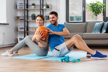 fitness, sport and healthy lifestyle concept - happy couple exercising with ball at home