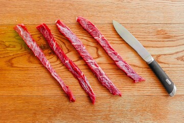 Carne cruda tagliata a strisce su un tavolo di legno con coltello d'acciaio sul lato