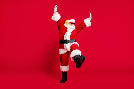 Can't Be Bothered. Full Length Photo Of Pensioner Old Man Grey Beard Hands Up Dance Wear Santa Costume Gloves Coat Belt Sunglass Headwear Earphones Black Boots Isolated Red Color Background