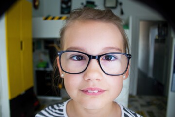 Ten-year-old pretty girl in black glasses looks straight into the lens.Shot of a cute and handsome girly face with glasses.