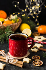 hot tea in a red mug in a new year's atmosphere. Christmas morning. A mug with a drink next to Christmas tree branches, oranges, spices and cookies